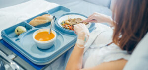 Mujer ingresada en la cama de un hospital comiendo comida casera